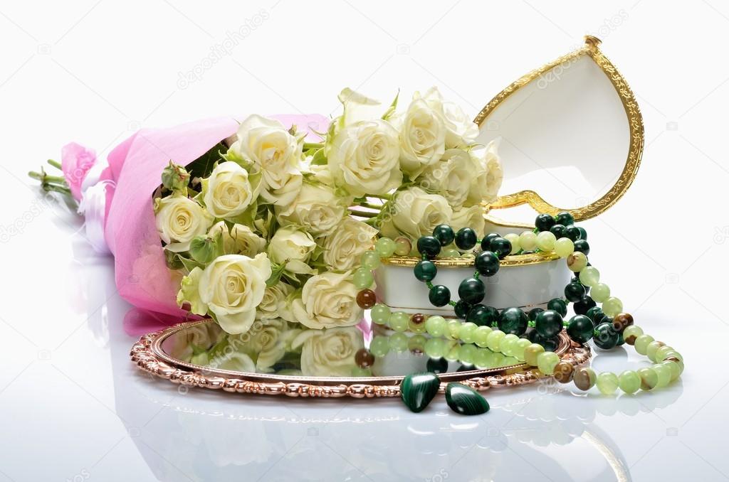 Women's jewelry, perfumes, cosmetics and a bouquet of flowers in still life