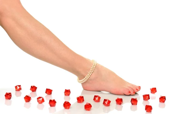 Perna de mulher bonita com pedicure vermelho em pregos e pulseira de pérola — Fotografia de Stock