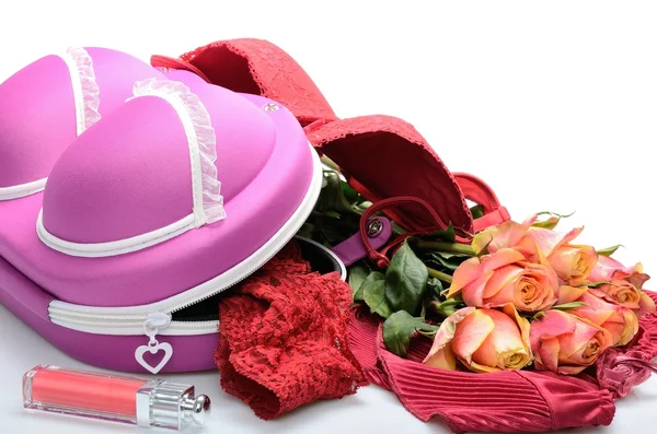 Vrouwelijke kleine koffer voor het opslaan van lingerie en roze bloemen in stilleven Stockafbeelding