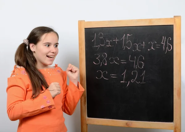 Tiener schoolmeisje in de buurt van een schoolraad verheugt zich correct op te lossen de vergelijking — Stockfoto