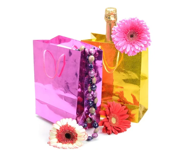 Geschenk pakken met een champagne fles, ketting en bloemen gerbera Stockfoto