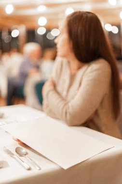 Bir kadın kahvaltı beklerken otel menüsü..