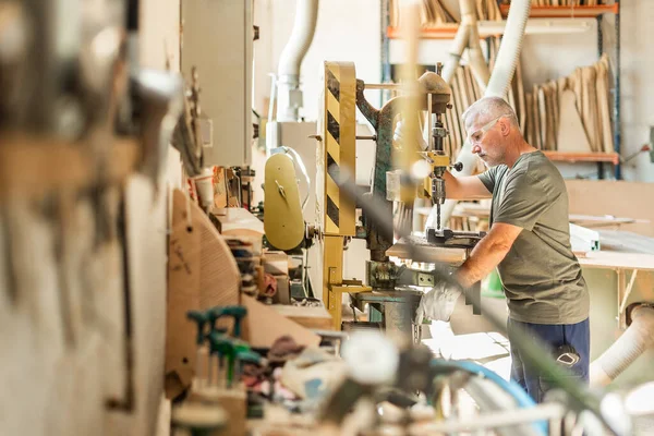 Ayakta duran adam arka planda metali delmeye odaklanmış.