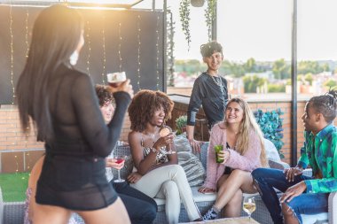 Mutlu çoklu etnik arkadaşlar terasta eğleniyor ve içiyorlar.