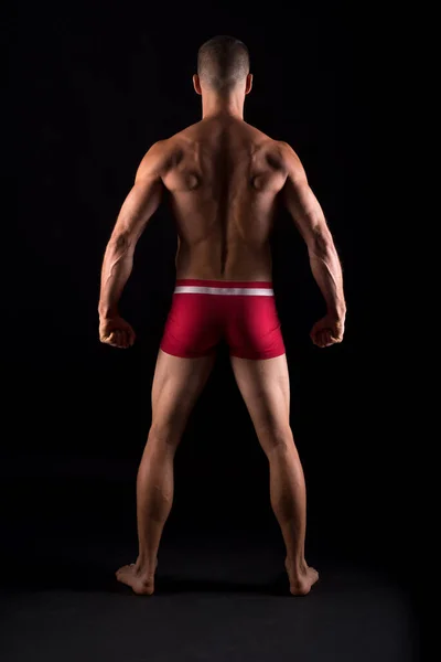 Studio photo of the back of strong man, black background — Stok fotoğraf