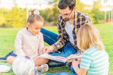A young single father reading a book to his children
