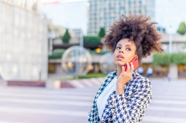 Dikkati dağılmış bir kadın telefonda konuşurken başka tarafa bakıyor.