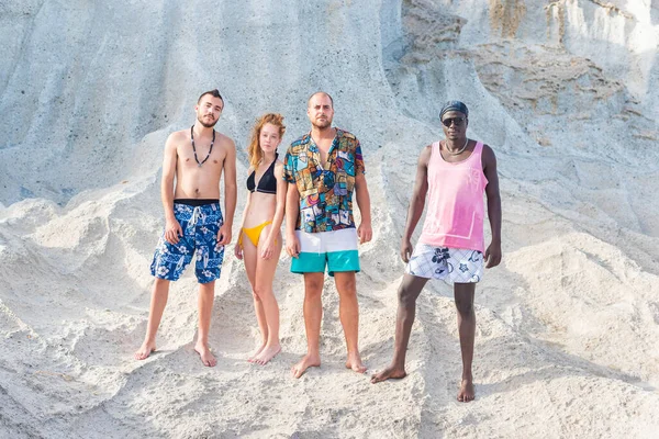Quatro amigos em roupas de verão posando em pé na praia — Fotografia de Stock
