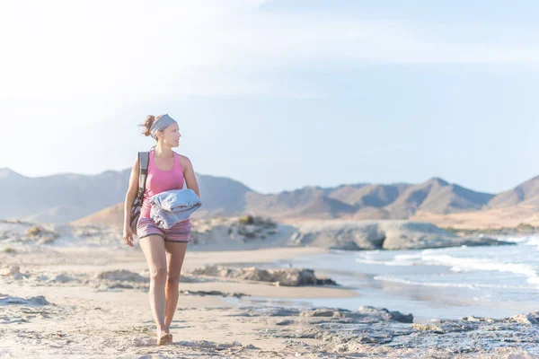 Расслабленная женщина, гуляющая по песчаному пляжу у моря — стоковое фото