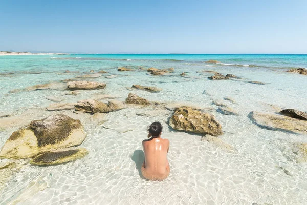 Γυμνή γυναίκα που κάθεται στη θάλασσα στην ακτή — Φωτογραφία Αρχείου
