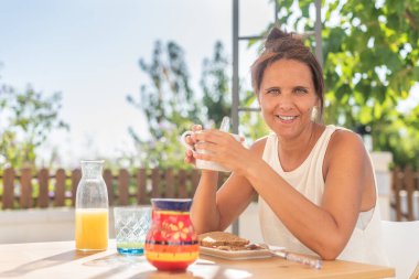 Kahvesini kahve, tost ve portakal suyuyla yapan neşeli kadın.