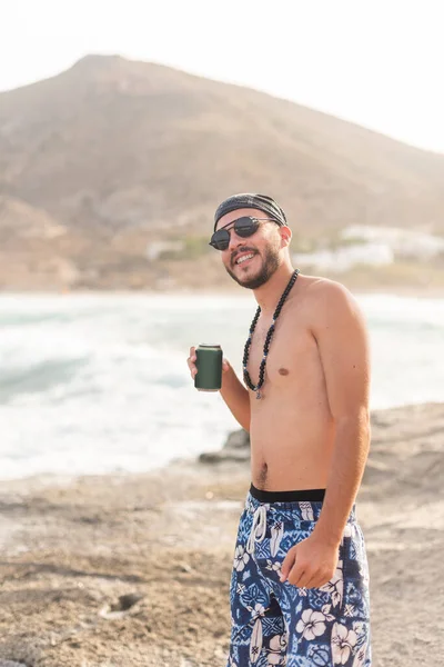 Male young adult in swimsuit posing happily with a drink — Stock Photo, Image