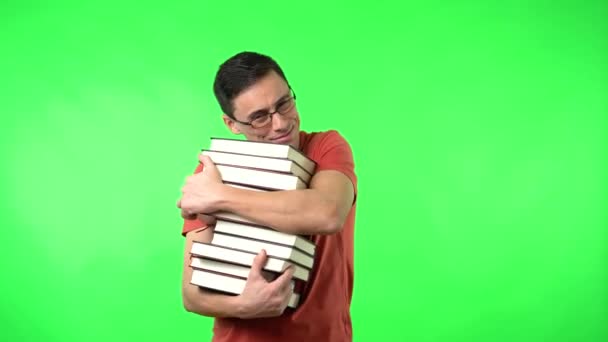 Feliz homem abraçando pilha de livros e sorrindo contra chromakey — Vídeo de Stock