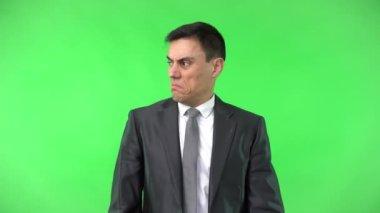 Zarif takım elbiseli bir adam stüdyoda burnunu sıkıyor.