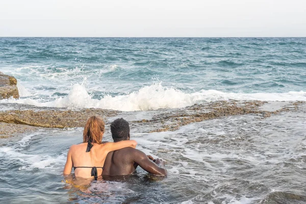 Casal tomando banho no mar abraçando uns aos outros — Fotografia de Stock