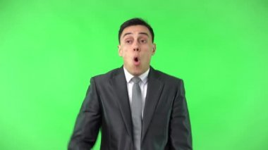 Şok olmuş şık takım elbiseli adam kameraya bakıyor.
