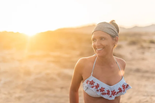 Веселая женщина на закате на песчаном пляже — стоковое фото