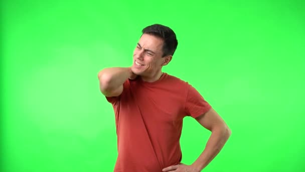 Brunet Mann massiert steifen Nacken, während er auf Chromakey steht — Stockvideo