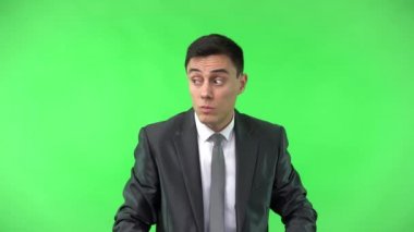 Resmi takım elbiseli adam parmaklarıyla ağzını kapatıyor.