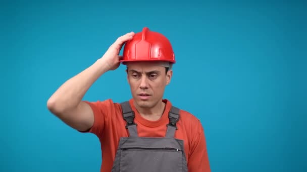 Tired male builder in uniform touching hardhat — ストック動画