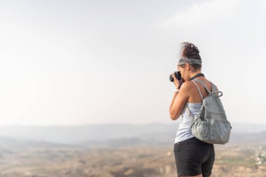 Sırt çantalı isimsiz bir kadın dağlarda fotoğraf çekiyor.