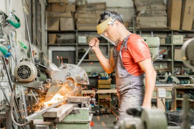 Tamirci atölyede çelik kesici kullanıyor.