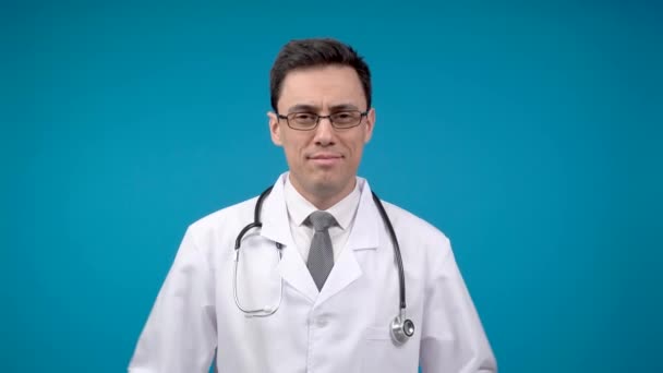 Glimlachende arts met gekruiste armen. Blauwe achtergrond — Stockvideo