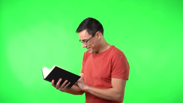 Egy szemüveges férfi könyvet olvas és mosolyog. — Stock videók