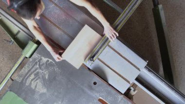 Sürgülü testere masasında çalışan yüzsüz marangoz.