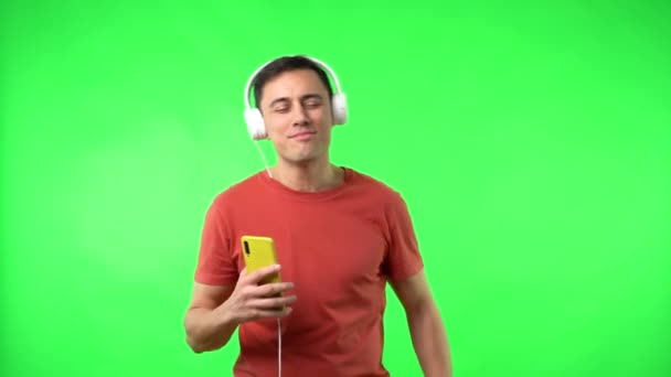 Позитивний хлопець з мобільним телефоном насолоджується музикою в навушниках — стокове відео