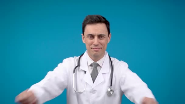 Θετικός ιατρός σταυρώνει τα χέρια σε μπλε φόντο — Αρχείο Βίντεο