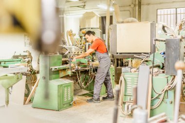 Atölyede ekipman üzerinde çalışan konsantre bir marangoz.