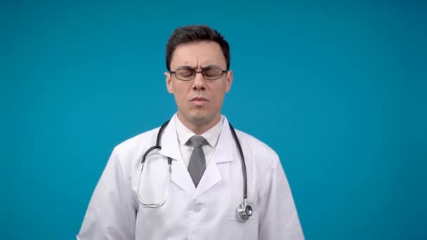 Strict doctor in glasses against blue backdrop — Vídeos de Stock
