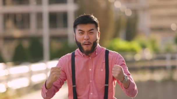幸せな中国の男は都市で空気中の拳を上げながら祝う — ストック動画