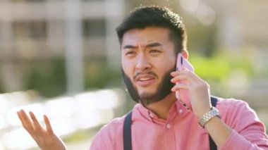 Sıradan giysileri olan şık Çinli bir adam şehirde cep telefonuyla konuşurken tartışıyor.