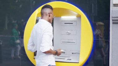 Afrikalı adam sokaktaki ATM 'den para çekiyor.