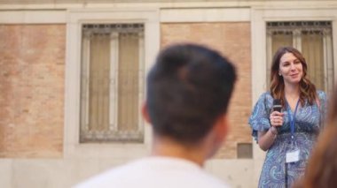 Çok ırklı bir gruba ünlü bir binayı gösteren kadın turist rehberi