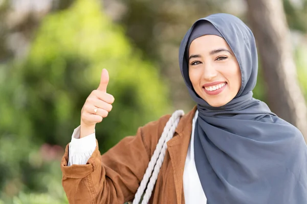 公園で親指で良いことをジェスチャーヒジャーブの笑みを浮かべてイスラム教徒の女性の肖像画 — ストック写真