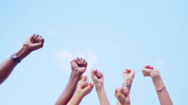 Different fists of people waving in the air with force