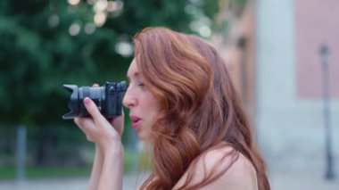 Açık havada fotoğraf çeken kızıl saçlı güzel bir kadının profili.