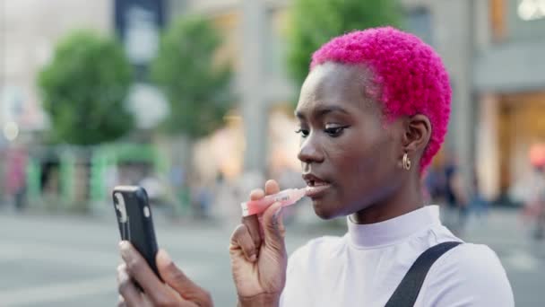 Afro Woman Applying Cream Her Lips Using Mobile Phone Screen — Video
