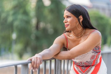 Parkta dikkati dağılmış transseksüel bir kadının portresi.