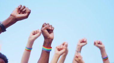 Igbt bilekliği takan ve kollarını sıkı tutan çok ırklı bir grup insanın kırpılmış görüntüsü.