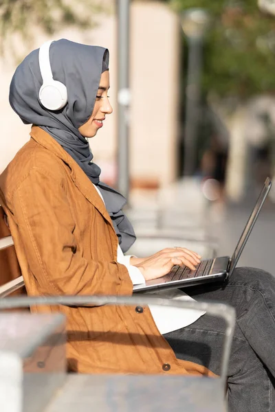 Vertical Photo Profile Muslim Woman Using Laptop Headphones Sitting Bench — Stock Fotó