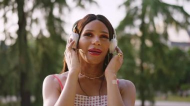 Transgender woman listening music and singing in a park