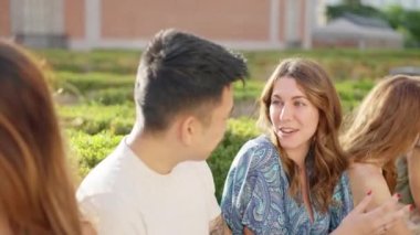 Chinese man and a caucasian woman talking in the street among a group of friends