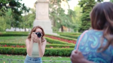 Kameralı bir kadın, bir grup arkadaşını sokağın ortasında fotoğraf çektirmek için bir araya getiriyor.