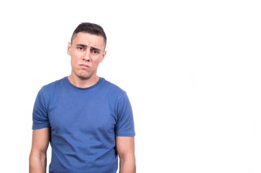 Üzgün bir ifadeyle ayakta duran bir adamın beyaz arka planlı stüdyo portresi.