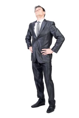 Kendine güvenen, zarif takım elbiseli ve kravatlı, elleri belinde beyaz arka planda duran ve kibirli bir şekilde kameraya bakan bir erkek yönetici.