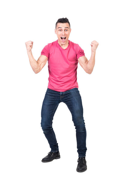 Full body happy male in jeans and pink t shirt clenching fists and looking at camera while celebrating victory isolated on white background